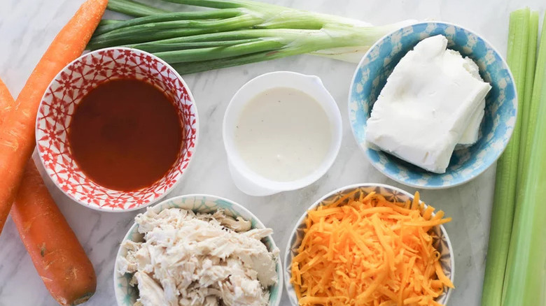 buffalo chicken dip ingredients in bowls on marble surface