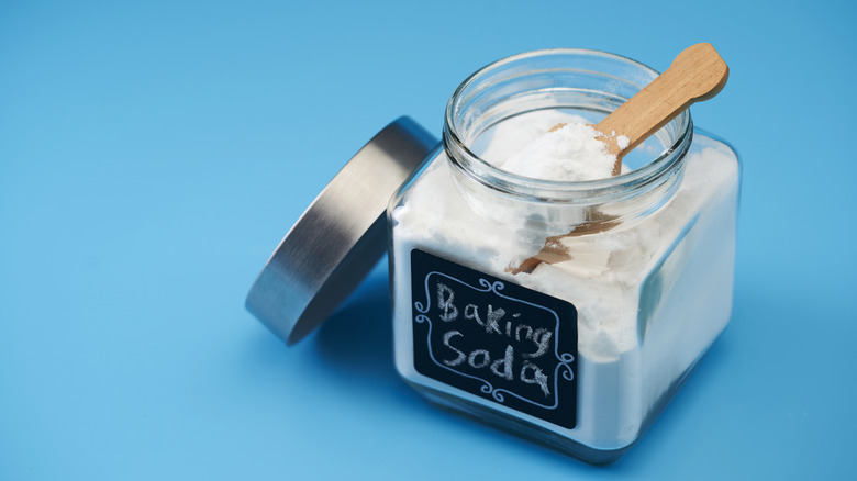 An open jar of baking soda placed against a blue background