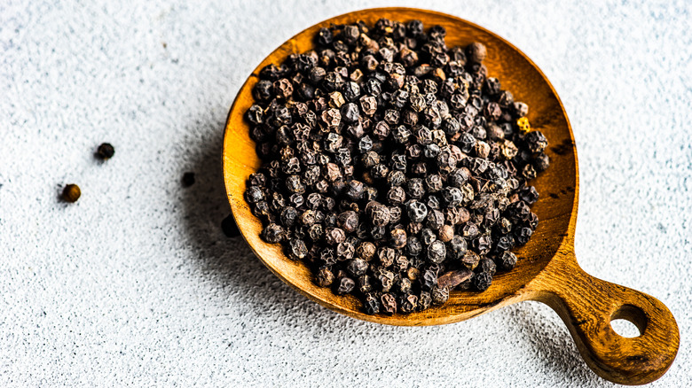 Black pepper placed in a bowl against a grey background