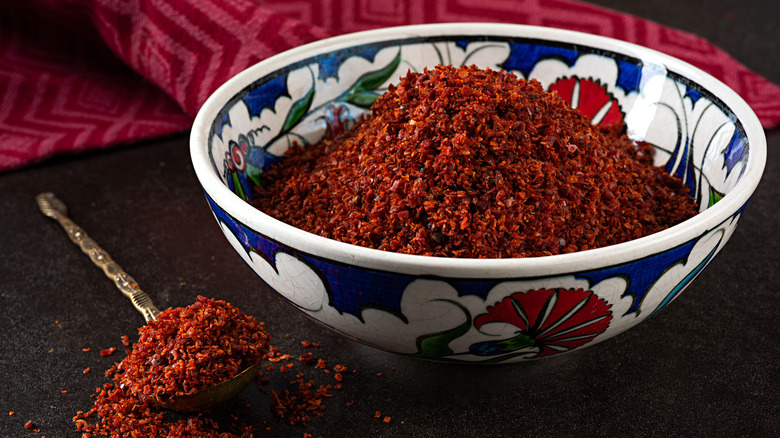 Cayenne pepper placed in a bowl and spoon on a black surface