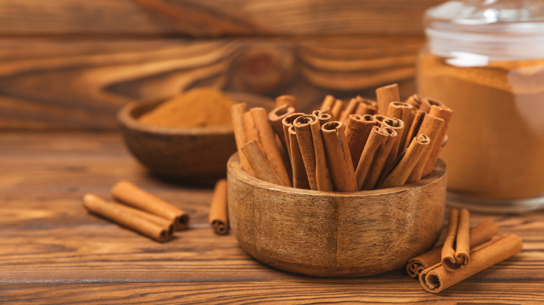 A cluster of cinnamon sticks placed in a bowl against a wooden background