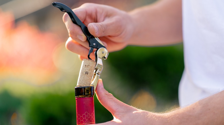 A sommelier opens a bottle of wine 