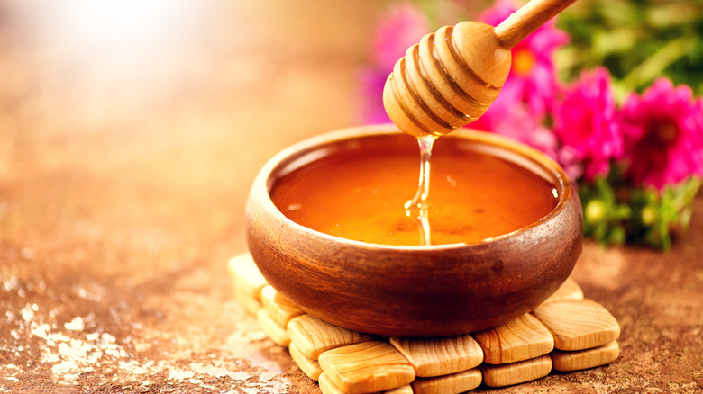 dripping honey in wooden bowl