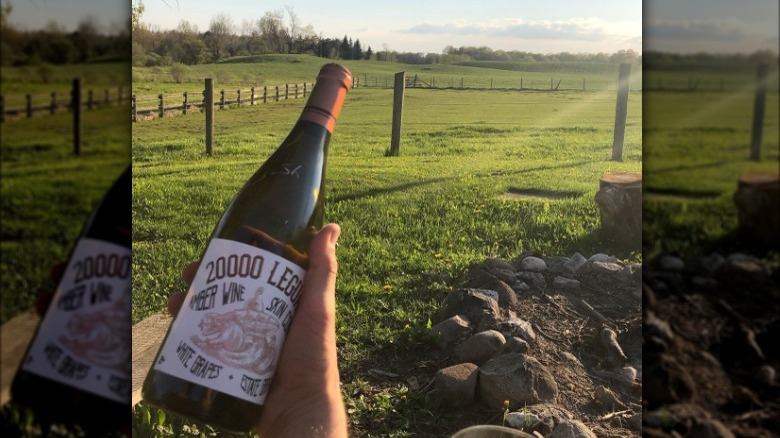 holding wine bottle in field