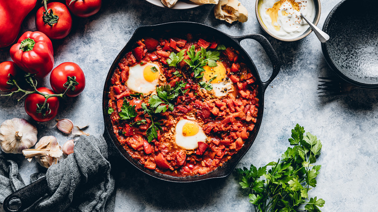 Top view of delicious shakshuka with eggs poached in a spicy sauce of tomatoes and vegetables