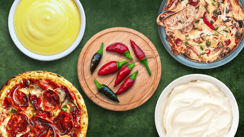 Calabrian chiles on wooden board surrounded by different dishes and sauces on green background