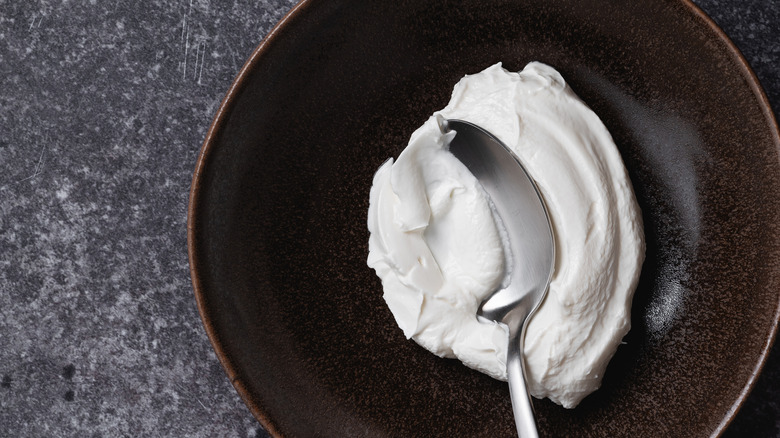 A bowl of homemade whipped ricotta on rustic grey surface viewed from above