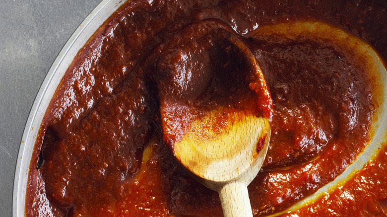 frying pan with tomato and vegetables sauce with a wooden spoon inside