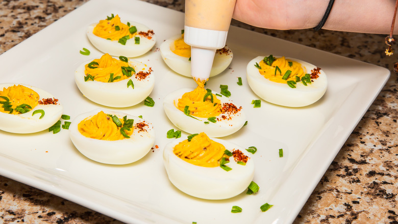 Person piping deviled egg yolks