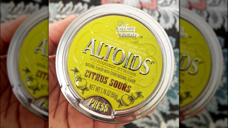 Hand holding yellow Altoids tin