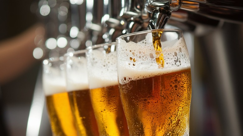 Beers being poured from a tap into glasses