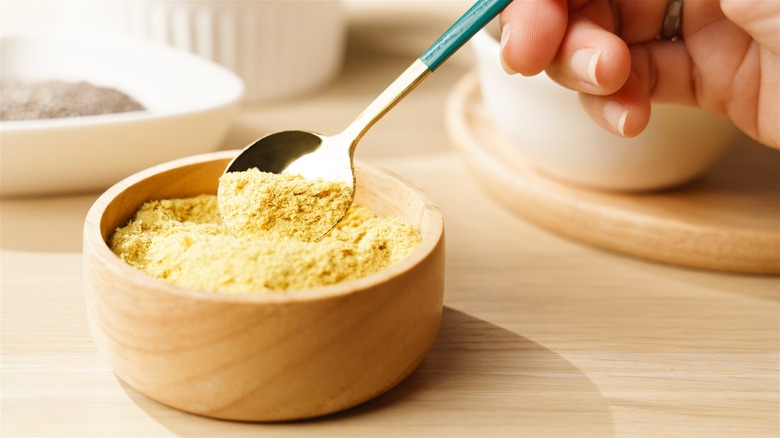 Taking a spoonful out of nutritional yeast bowl