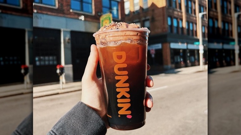 holding Dunkin' iced coffee