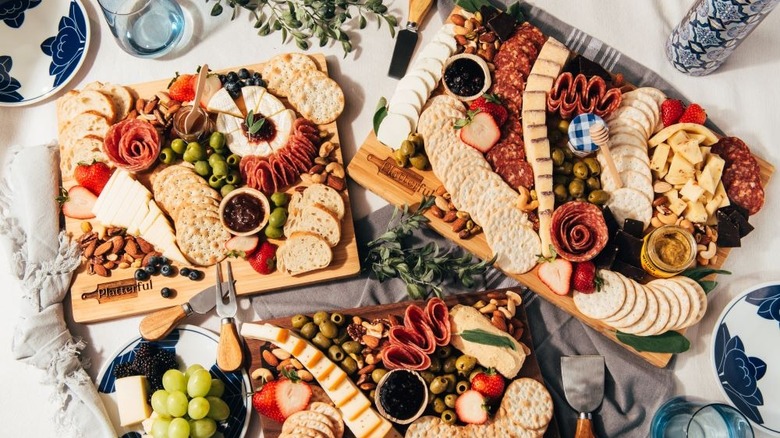 Three charcuterie boards with cheese, meat, crackers, and fruit