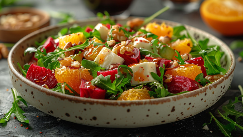 a bowl of rocket salad with fruit, cheese, and vegetables