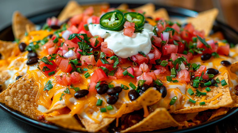 a bowl of cheesy nachos covered in fresh ingredients