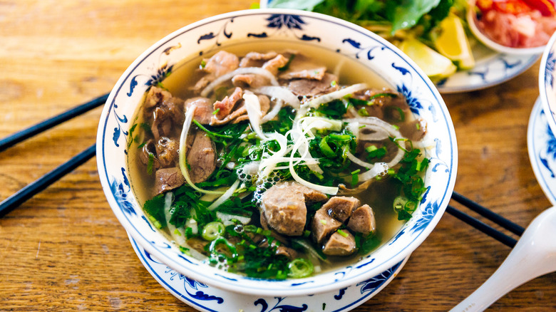 a bowl of pho noodle soup on wooden surface