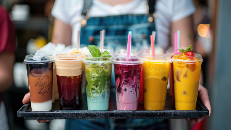 a woman holding a tray of various smoothies