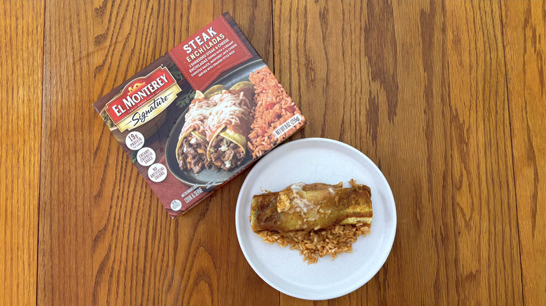 El Monterey steak enchilada with spanish rice on white plate on wooden table