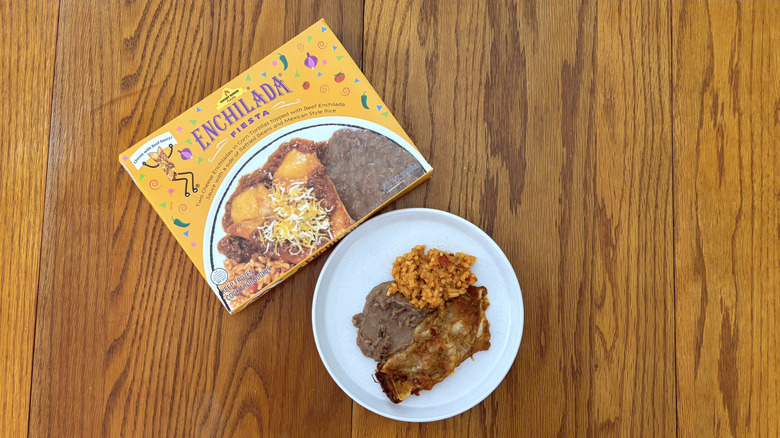 Night Hawk cheese enchilada with beef sauce refried beans and spanish rice on white plate on wooden table