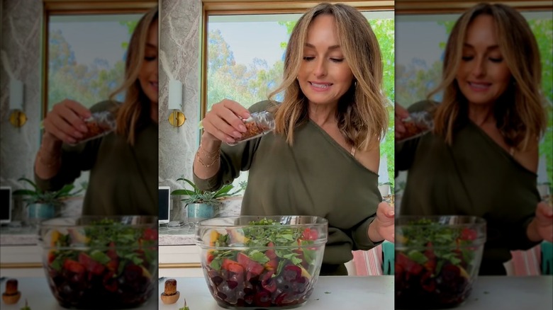 Giada De Laurentiis putting red pepper on a fruit salad