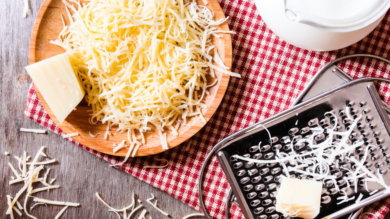 Bowl of grated parmesan cheese with grater