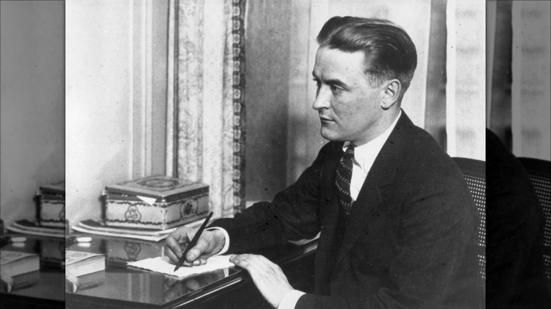 Black and white portrait of F. Scott Fitzgerald sitting at writing desk