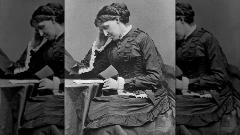 Black and white portrait of Louisa May alcott sitting at writing desk