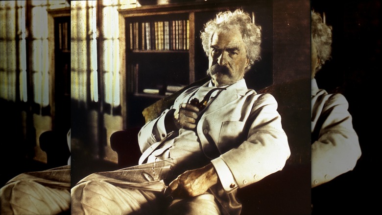 Colorized photograph of Mark Twain sitting in chair holding pipe