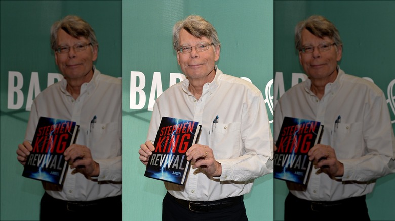 Stephen King standing holding book Revival