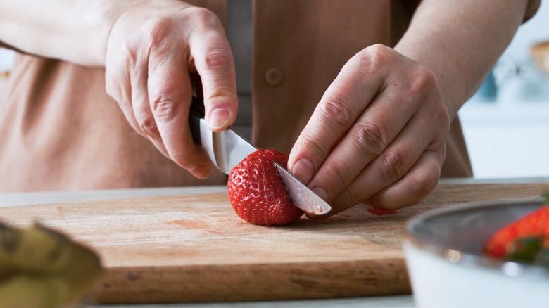 hands slicing a strawberry