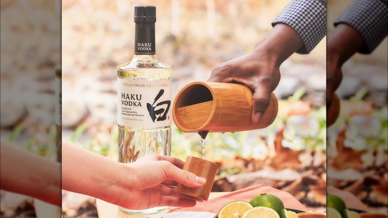 Haku vodka bottle with people pouring a shot outside