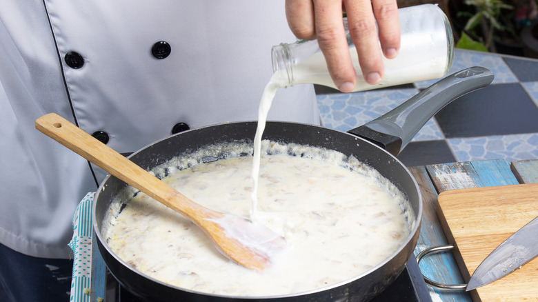 Chef pouring milk into soup