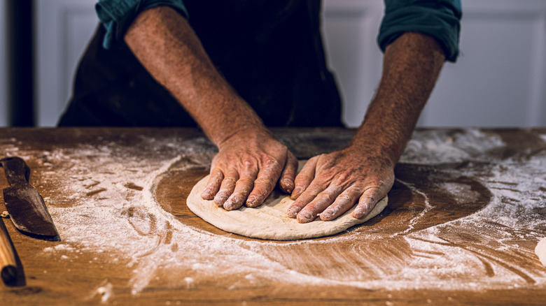 Two hands pressing pizza dough