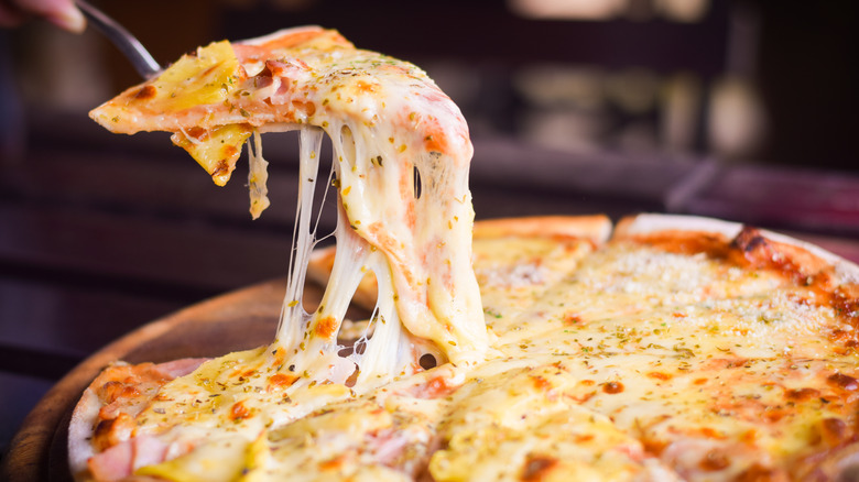 Cheesy pizza slice being lifted