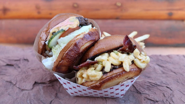 Two burgers on a cardboard tray including mac and cheese burger