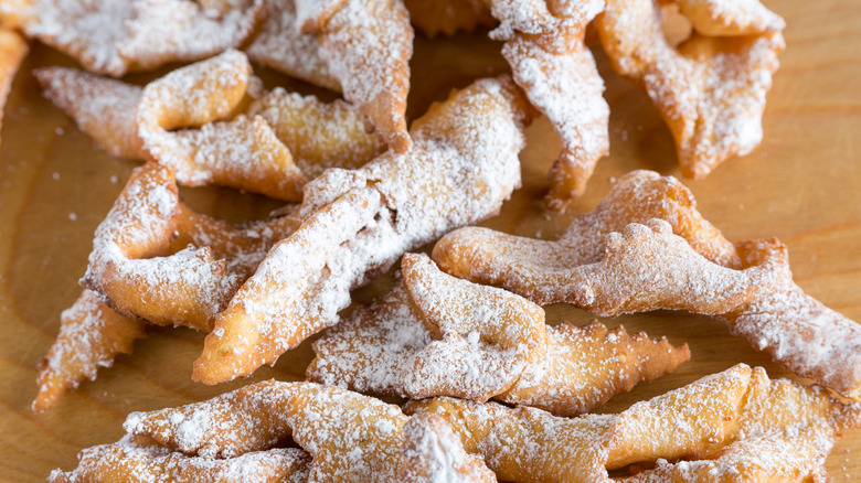 Sugar-dusted fattigmann cookies on wooden board