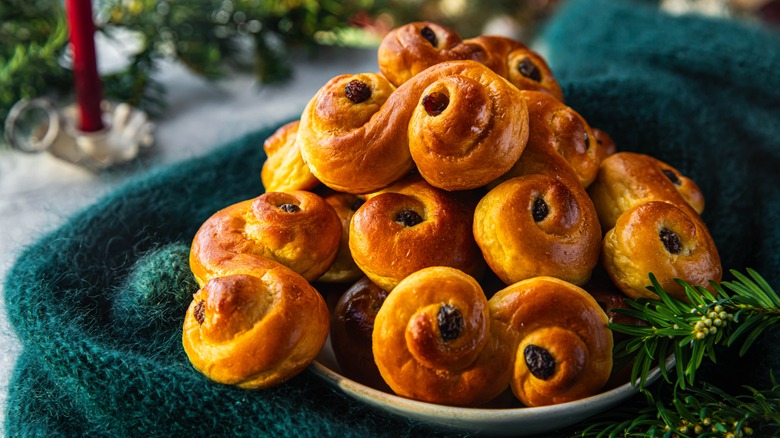 Lussekatter piled on a plate surrounded by Christmas decorations