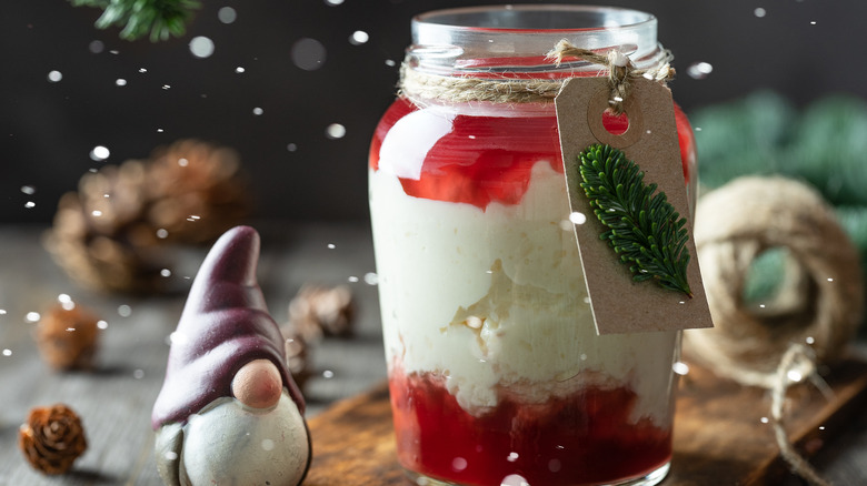 Riskrem in a jar with red fruit sauce, surrounded by Christmas decorations