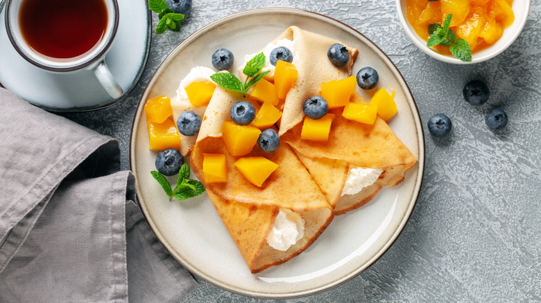 Sweet crepes with blueberries, mango and whipped cream