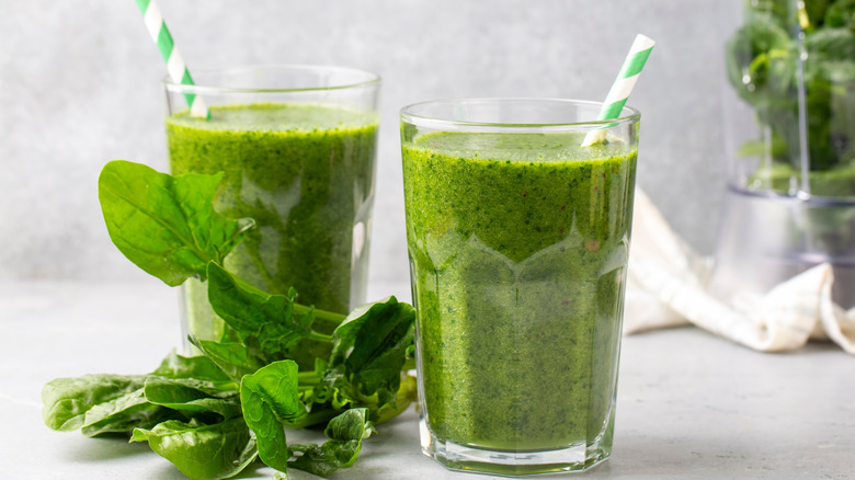 Two glasses of green juice with spinach leaves