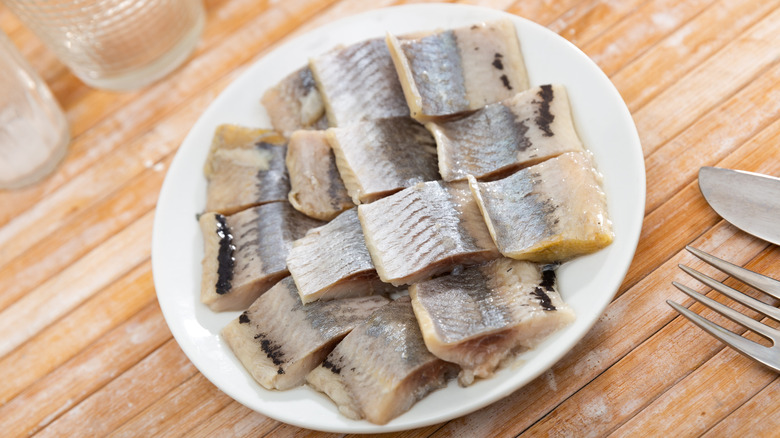 Pieces of pickled herring presented on white plate