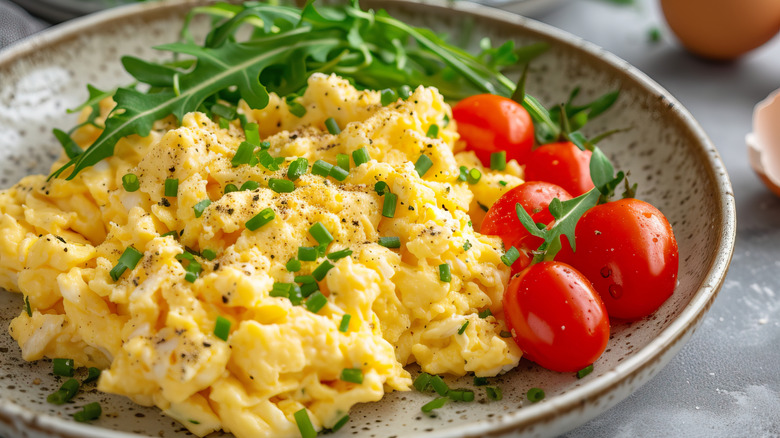 Fluffy scrambled eggs with tomatoes and rocket