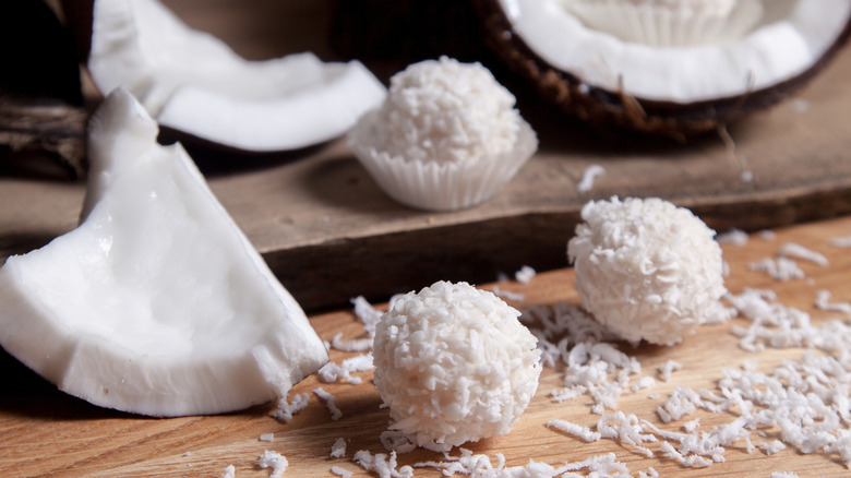 Coconut truffles with broken fresh coconut shells in background