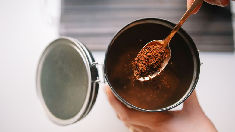 Hand holding spoonful of instant coffee granules