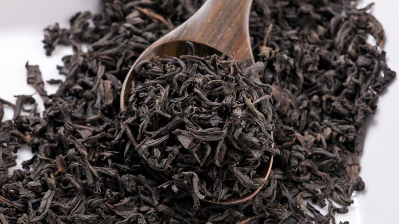 Dried loose black tea leaves with wooden spoon