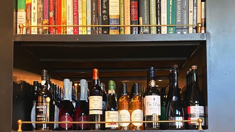 Two shelves lined with books and wine