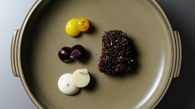 A minimalist pate of cured, wild rice, pineapple taffy, and hearts of palm at Alinea, Chicago