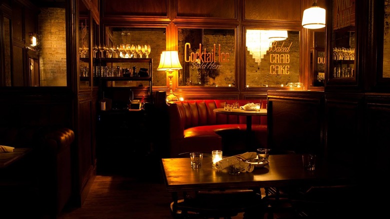 Dim-lit wooden interior of Bavette's, Chicago, with a red booth and vintage lamps