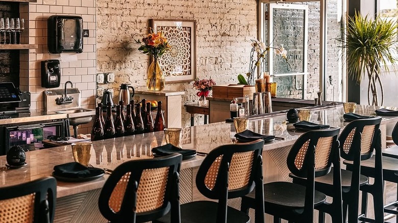 The bar section with wooden high chairs and plants at Mirra, Chicago